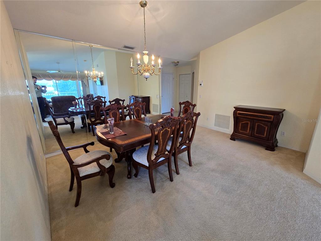 A dining room features a wooden table with chairs, a chandelier, and a mirrored wall — 5800 SABAL TRACE DRIVE UNIT 1002, NORTH PORT, FL