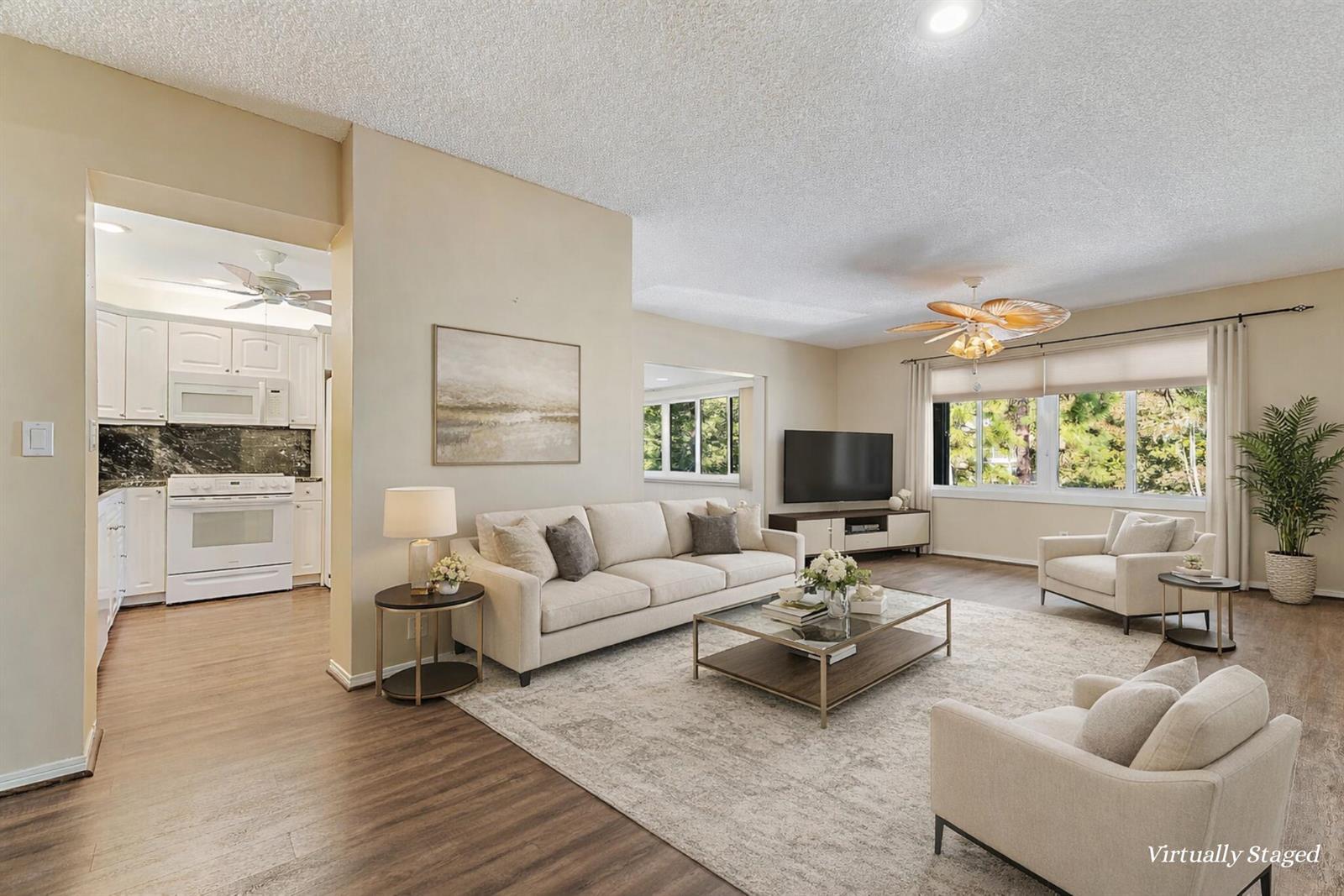 A living room with a beige sofa, two armchairs, a glass coffee table, and wood flooring — 1800 SE Saint Lucie Boulevard # 201, Stuart FL 34996, STUART, FL