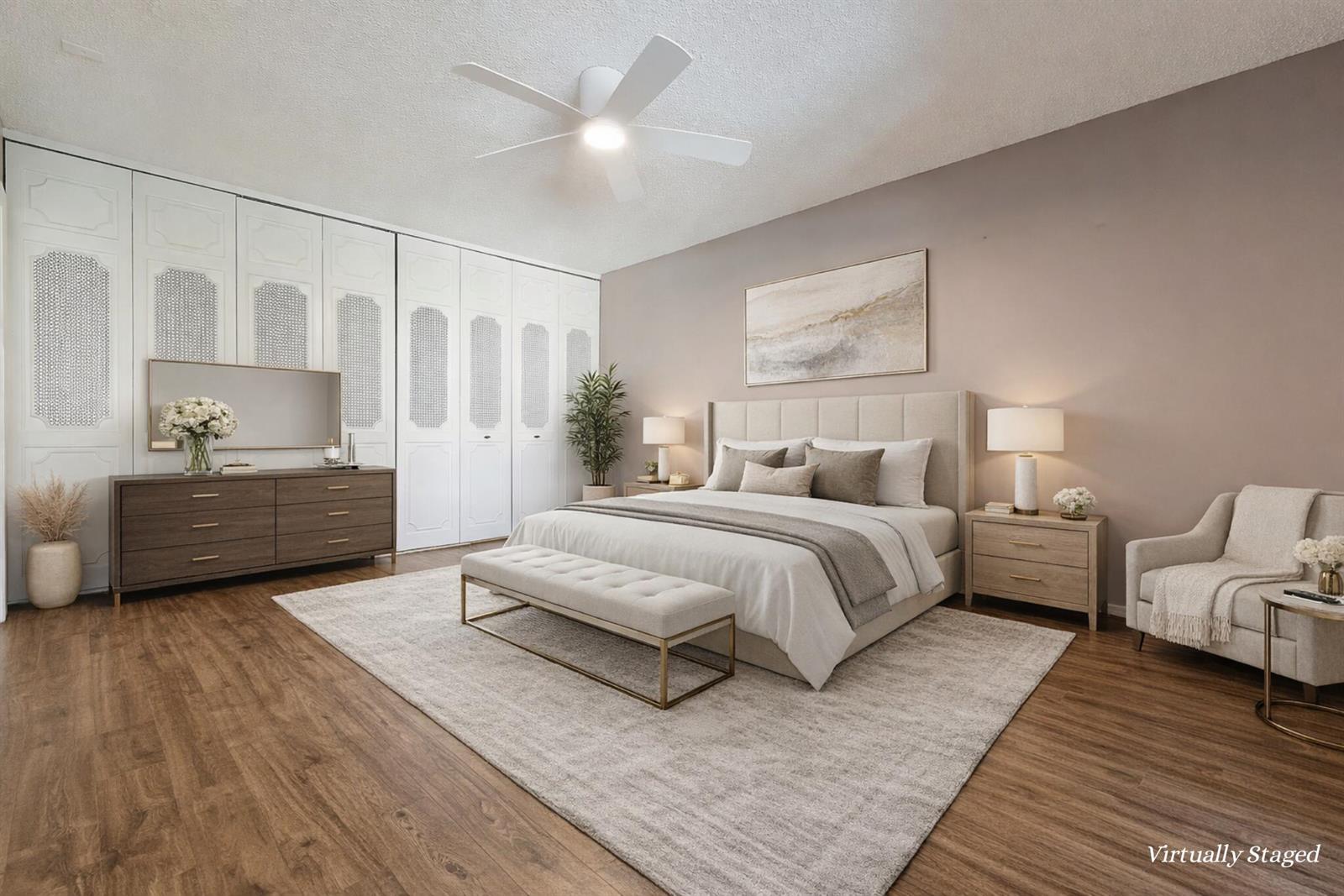 This virtually staged bedroom features a bed, dresser, and white paneled closets on wood flooring — 1800 SE Saint Lucie Boulevard # 201, Stuart FL 34996, STUART, FL