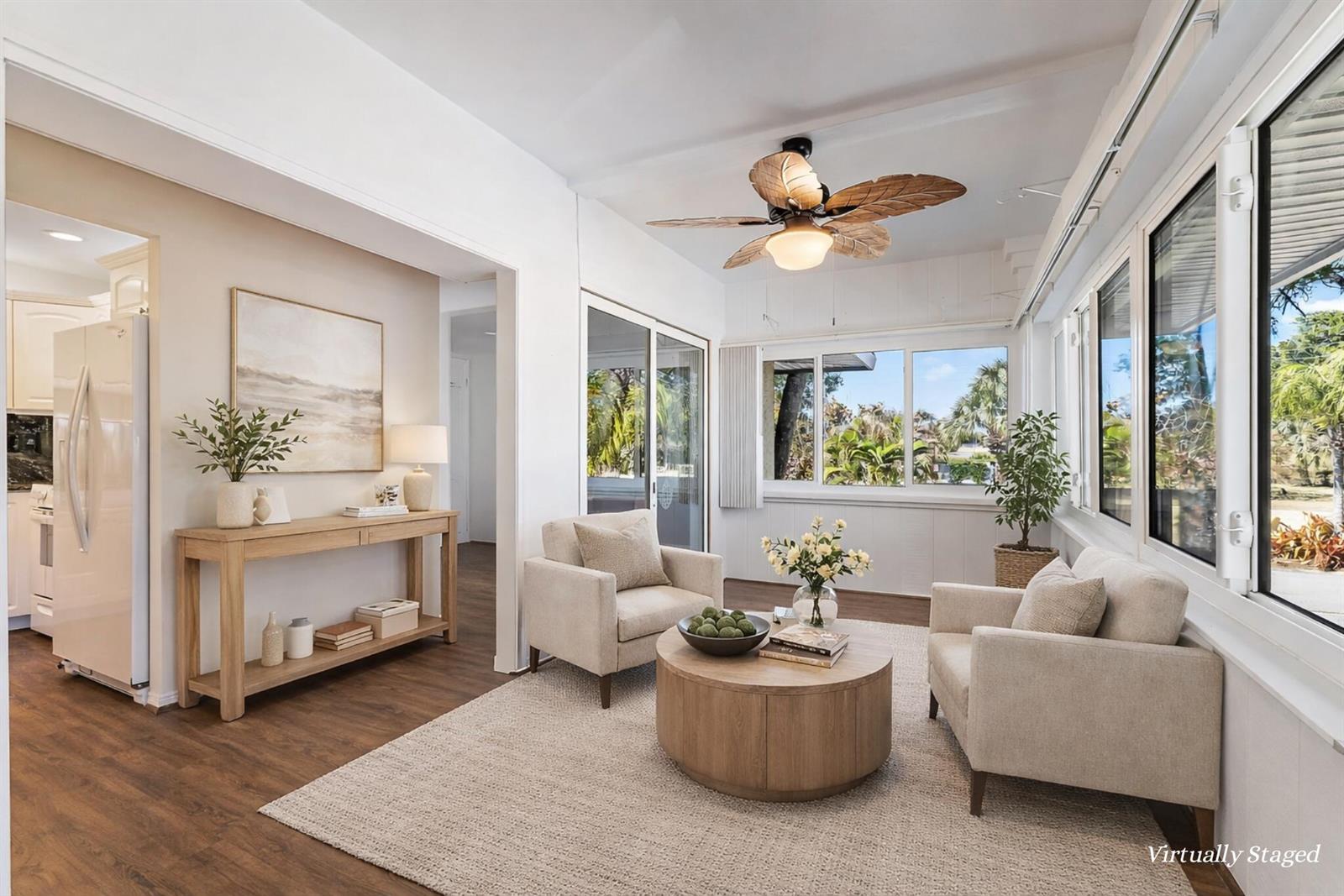 A sunroom features two beige armchairs, a round wooden coffee table, and a ceiling fan — 1800 SE Saint Lucie Boulevard # 201, Stuart FL 34996, STUART, FL