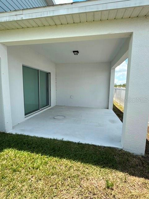 A covered concrete patio features a sliding glass door and a ceiling light fixture — 1062 SAND TORCH CIRCLE, DAVENPORT, FL