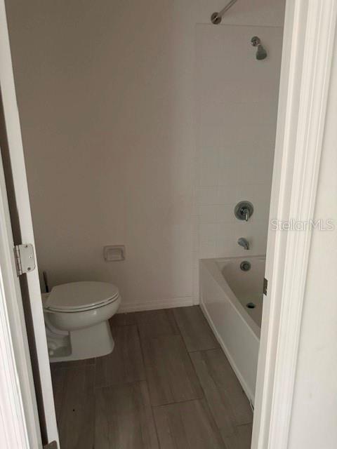 A bathroom features a white toilet, a bathtub with a shower head, and tiled flooring — 1062 SAND TORCH CIRCLE, DAVENPORT, FL
