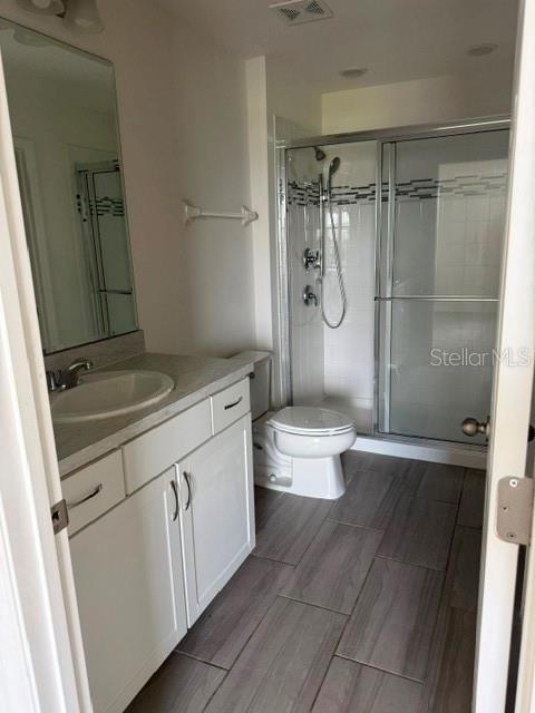 A bathroom features a white vanity, a mirror, a glass shower, and wood-look tile flooring — 1062 SAND TORCH CIRCLE, DAVENPORT, FL