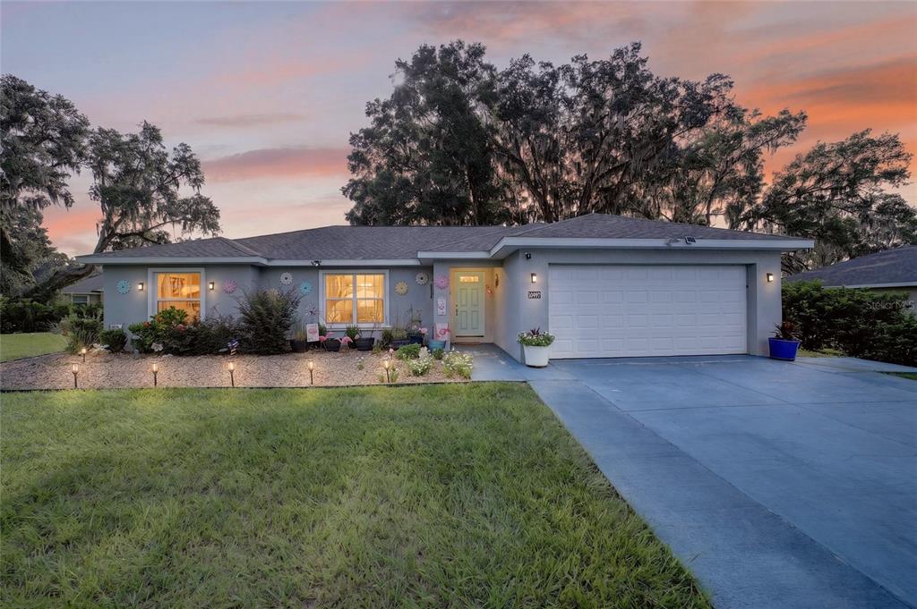 A single-story house with a gray exterior, a two-car garage, and a landscaped front yard — 10097 SW 78TH COURT, OCALA, FL