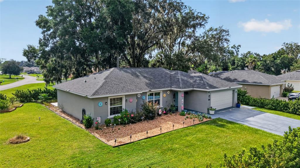 An exterior view of a single-story gray house with a shingled roof and landscaped yard — 10097 SW 78TH COURT, OCALA, FL