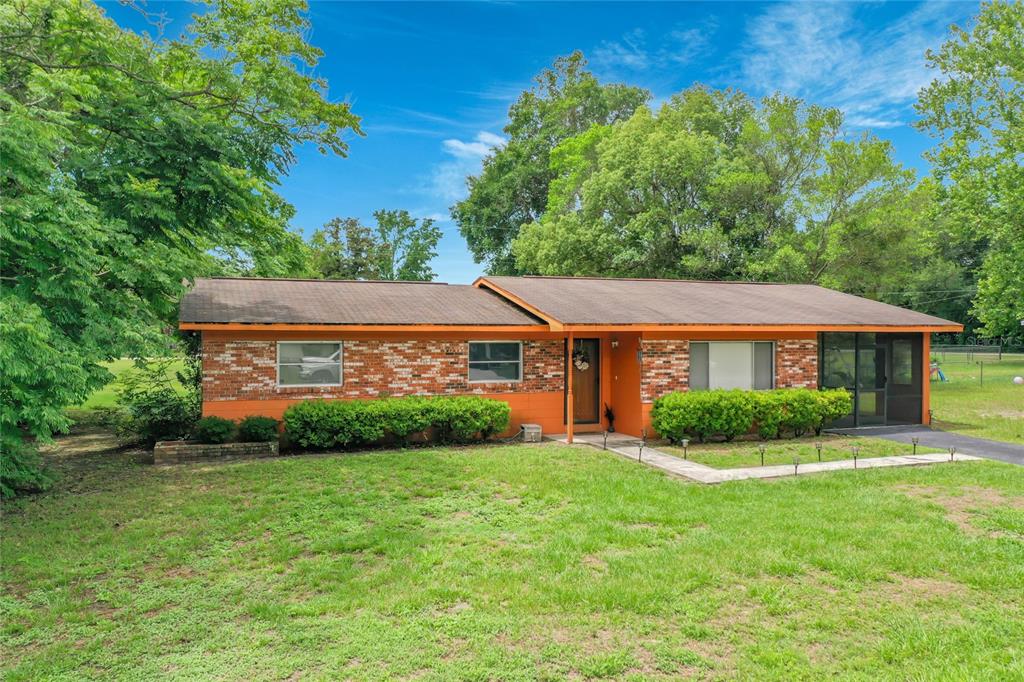 A single-story house with orange brick and siding, a brown roof, and a front lawn — 910 NE 45TH STREET, OCALA, FL