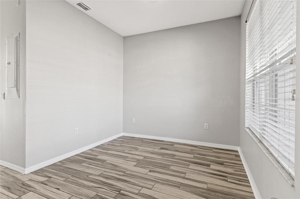 An empty room with light gray walls, wood-look tile flooring, and a large window with blinds — 8874 CHRISTIE DRIVE, LARGO, FL