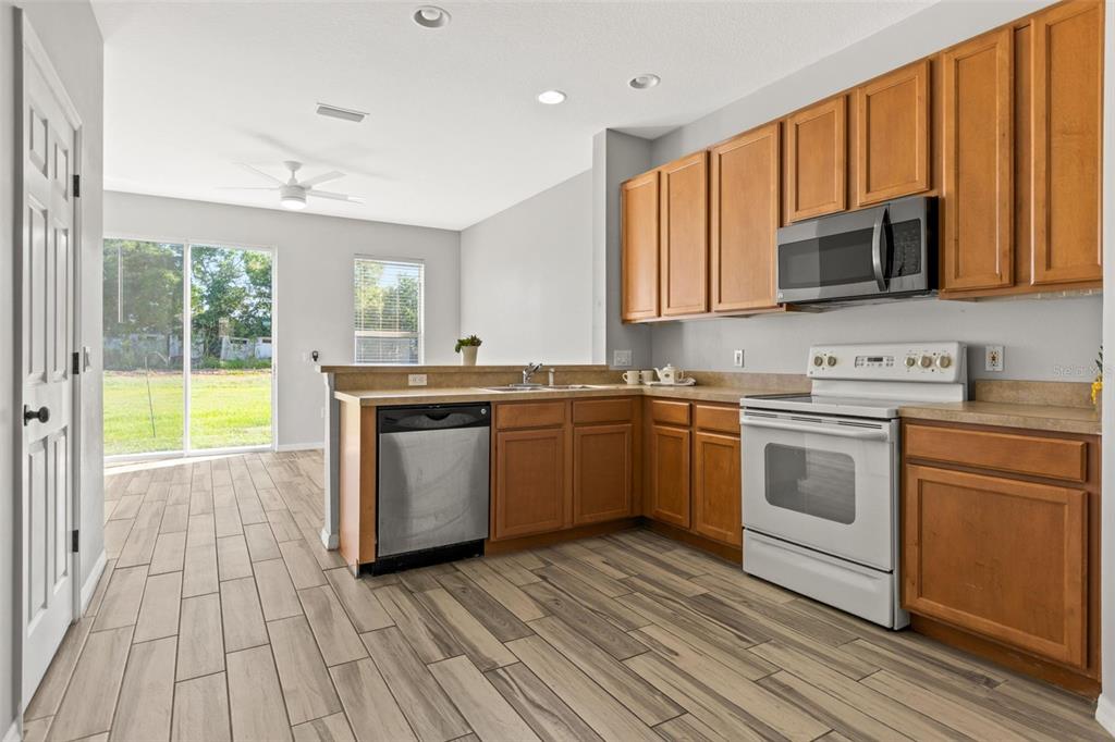 A kitchen with wood cabinets, white appliances, and light-colored wood-look tile flooring — 8874 CHRISTIE DRIVE, LARGO, FL