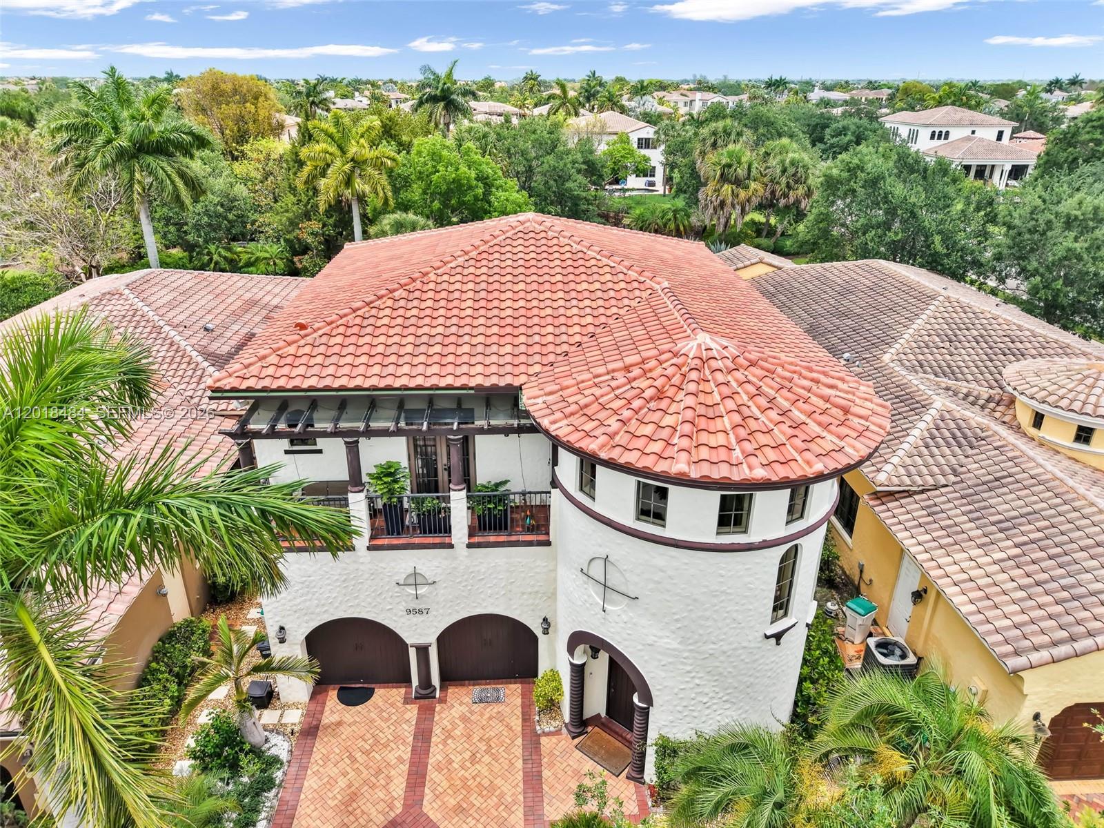 An aerial view shows a two-story house with a circular tower and red tile roof — 9587 Exbury Ct, Parkland FL 33076, PARKLAND, FL