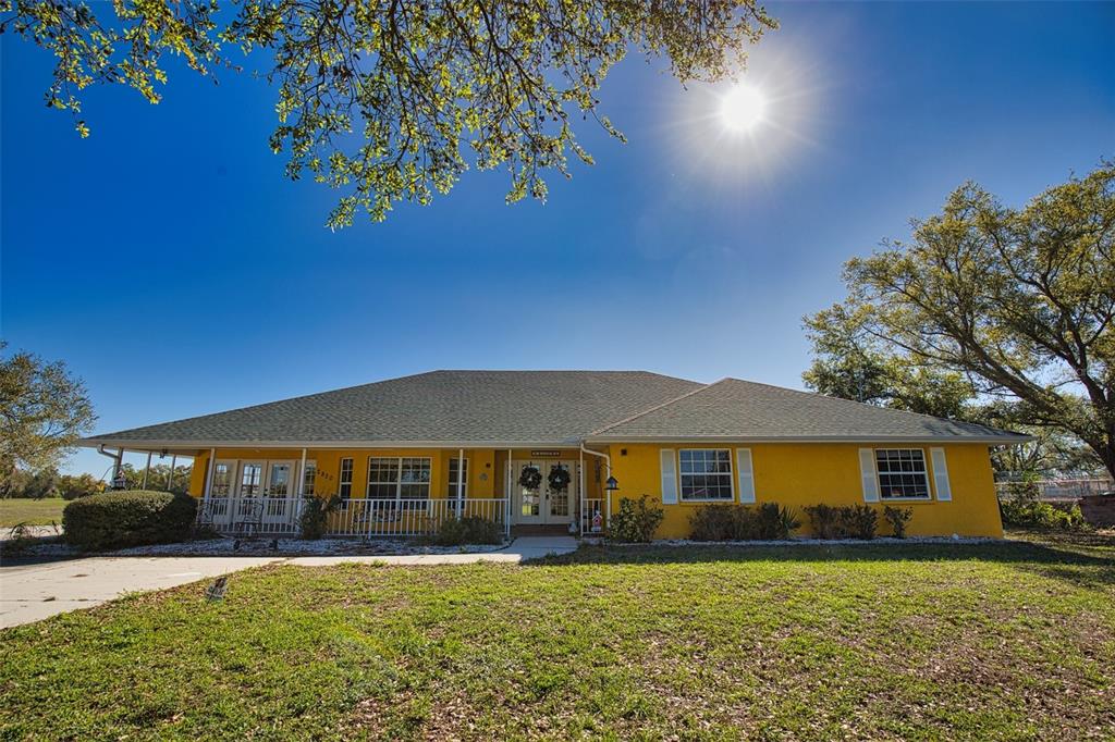 A yellow single-story house with a wide porch and a large lawn under a sun — 2820 PAN AMERICAN BOULEVARD, NORTH PORT, FL