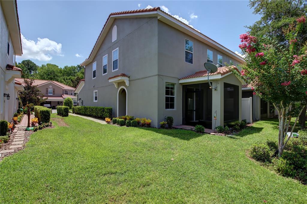 The exterior of a two-story house features a screened-in patio and a grassy backyard — 266 TERRACINA DRIVE, SANFORD, FL