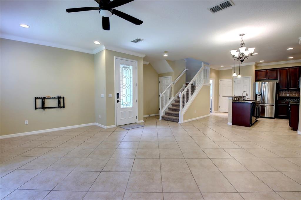 An open-concept living area features tile flooring, a staircase, and an adjacent kitchen — 266 TERRACINA DRIVE, SANFORD, FL