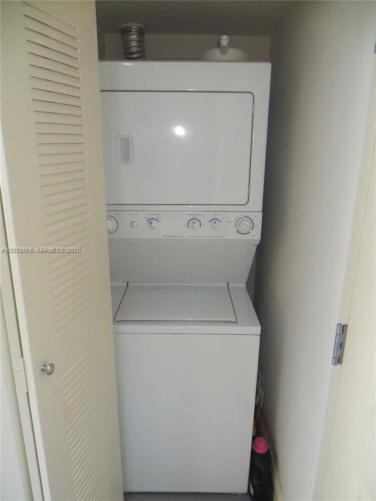 A white stacked washer and dryer unit is located inside a closet — 111 E Flagler St # 402, Miami FL 33131, MIAMI, FL