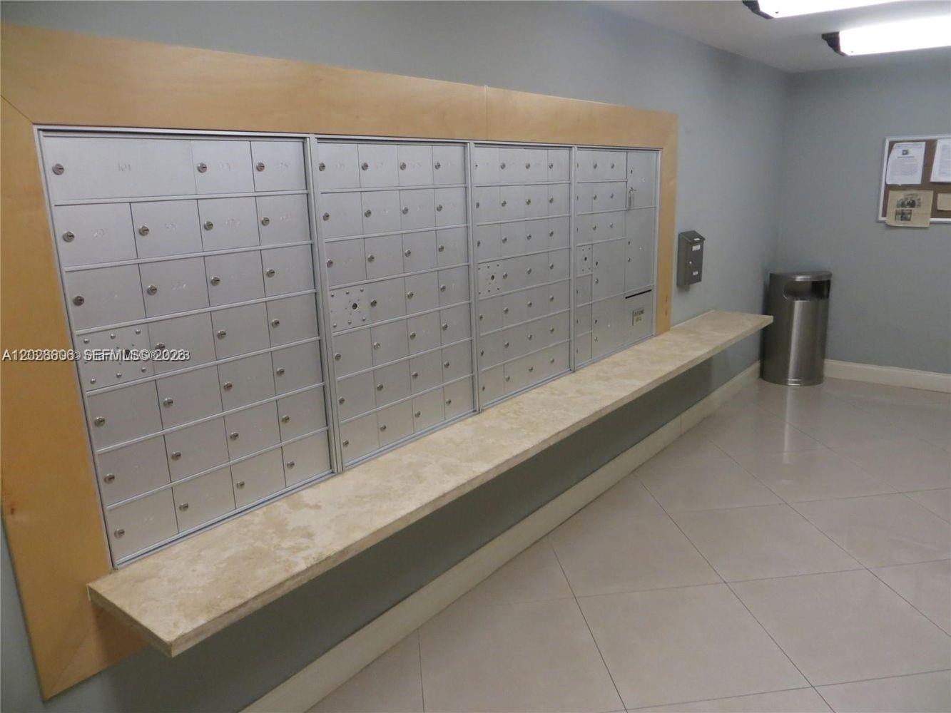 A mailroom features rows of metal mailboxes mounted on a wall above a stone counter — 111 E Flagler St # 402, Miami FL 33131, MIAMI, FL