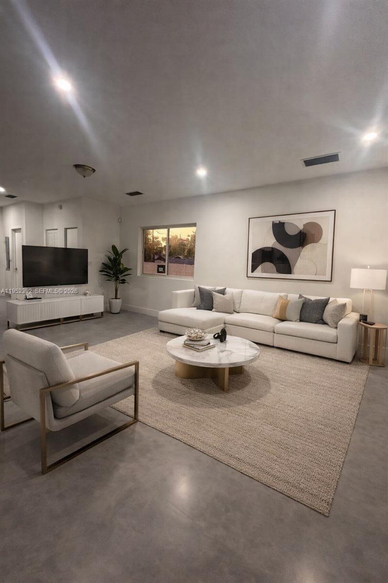 A modern living room features a white sectional sofa, marble coffee table, and concrete flooring — FORT LAUDERDALE, FL