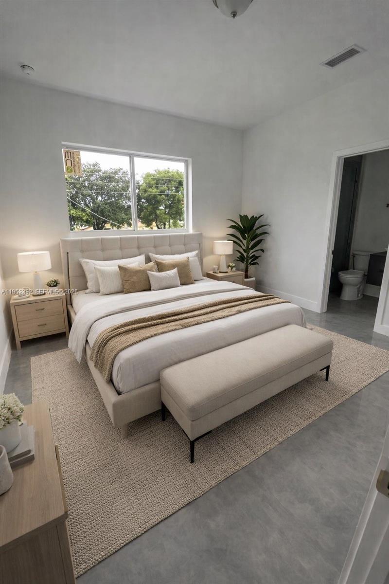 A modern bedroom features a tufted headboard, a neutral rug, and an attached bathroom — FORT LAUDERDALE, FL