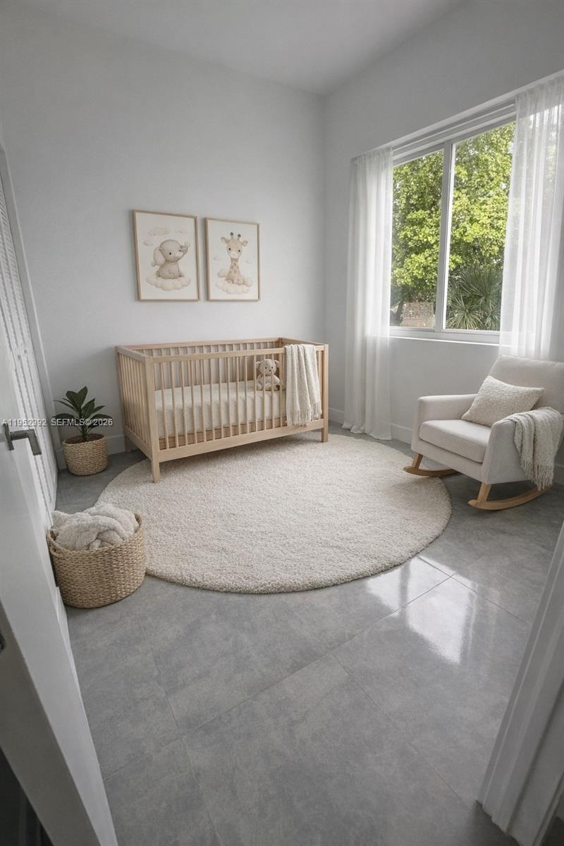A nursery features a wooden crib, a rocking chair, and a round rug on tile — FORT LAUDERDALE, FL