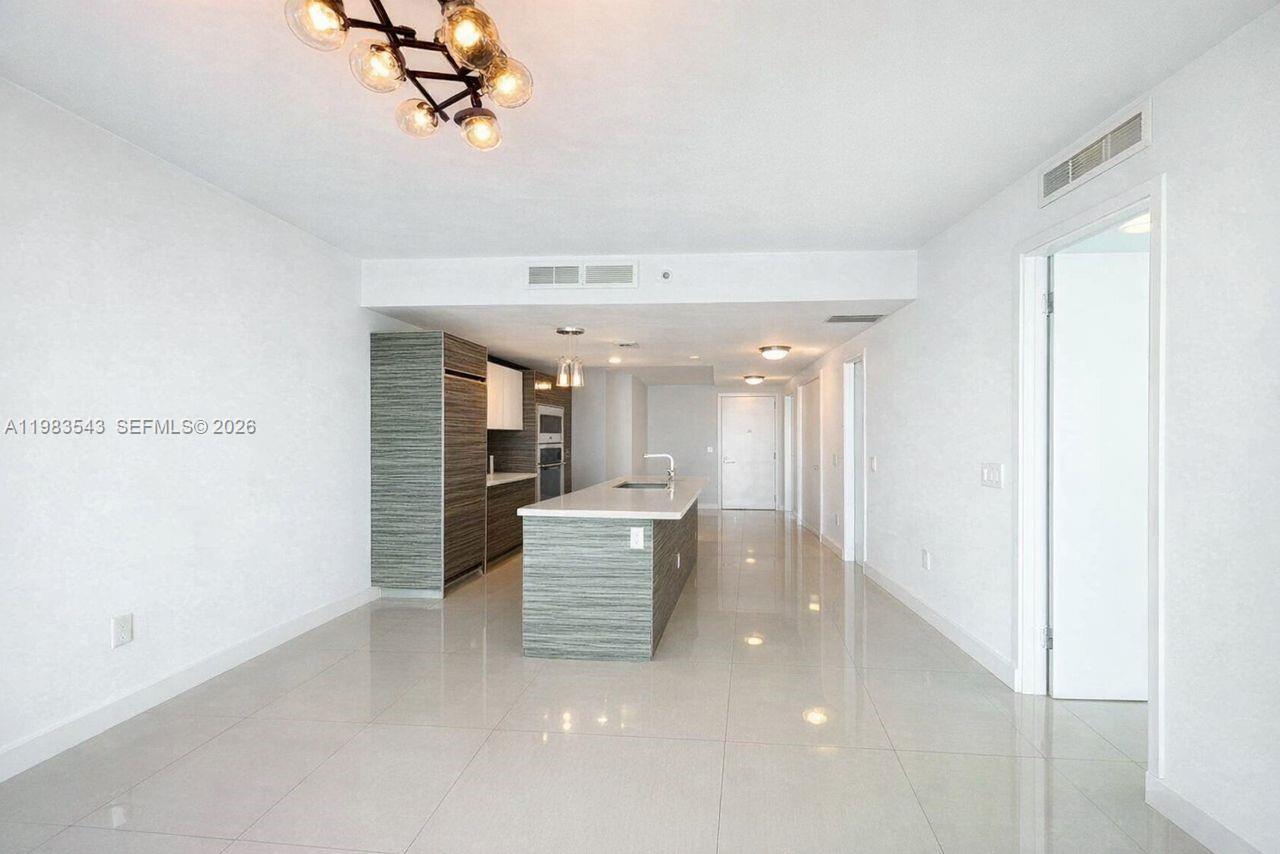 A modern kitchen features a white quartz island, wood-grain cabinetry, and floor-to-ceiling windows — 460 NE 28th St # 1407, Miami FL 33137, MIAMI, FL