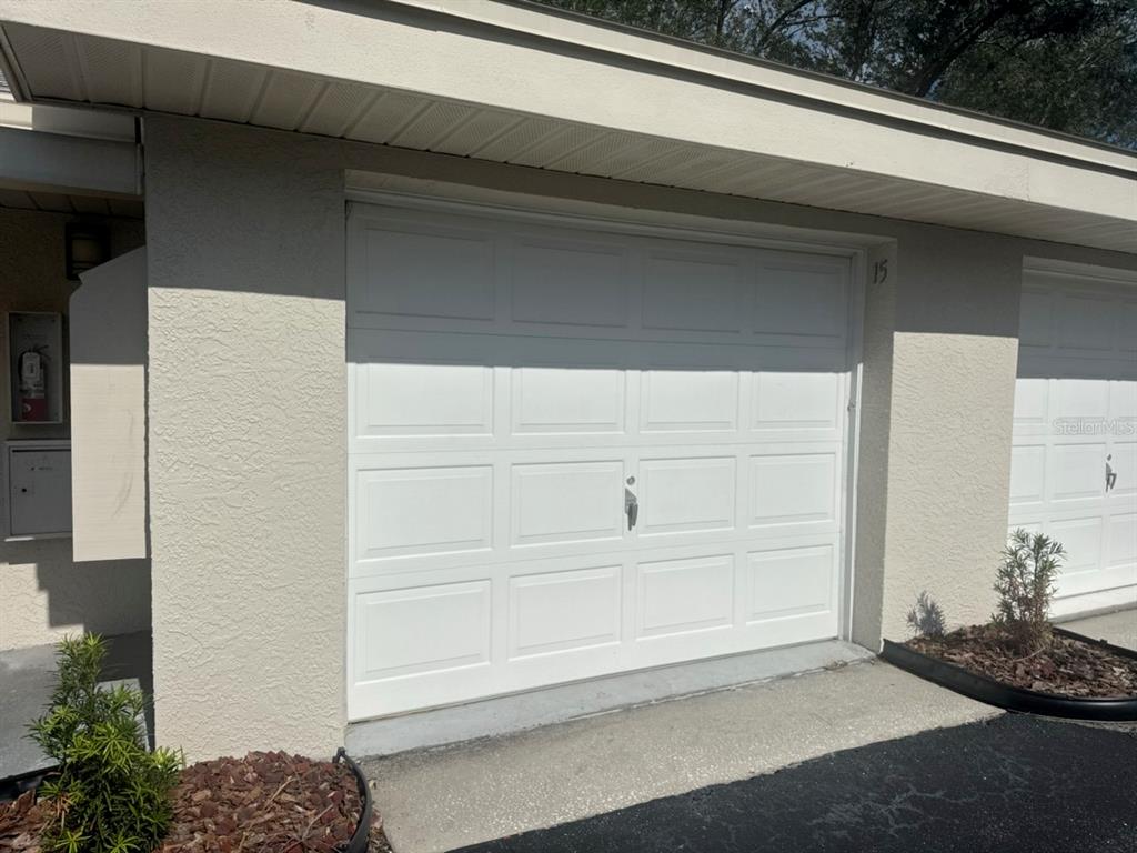 A white garage door with the number 15 is set into a beige stucco exterior — 1312 PASADENA AVENUE S UNIT 15, ST PETERSBURG, FL