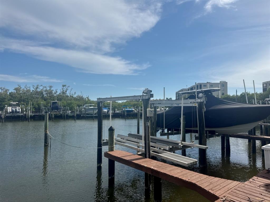 A boat lift with a covered boat sits at a wooden dock on a canal — 1312 PASADENA AVENUE S UNIT 15, ST PETERSBURG, FL