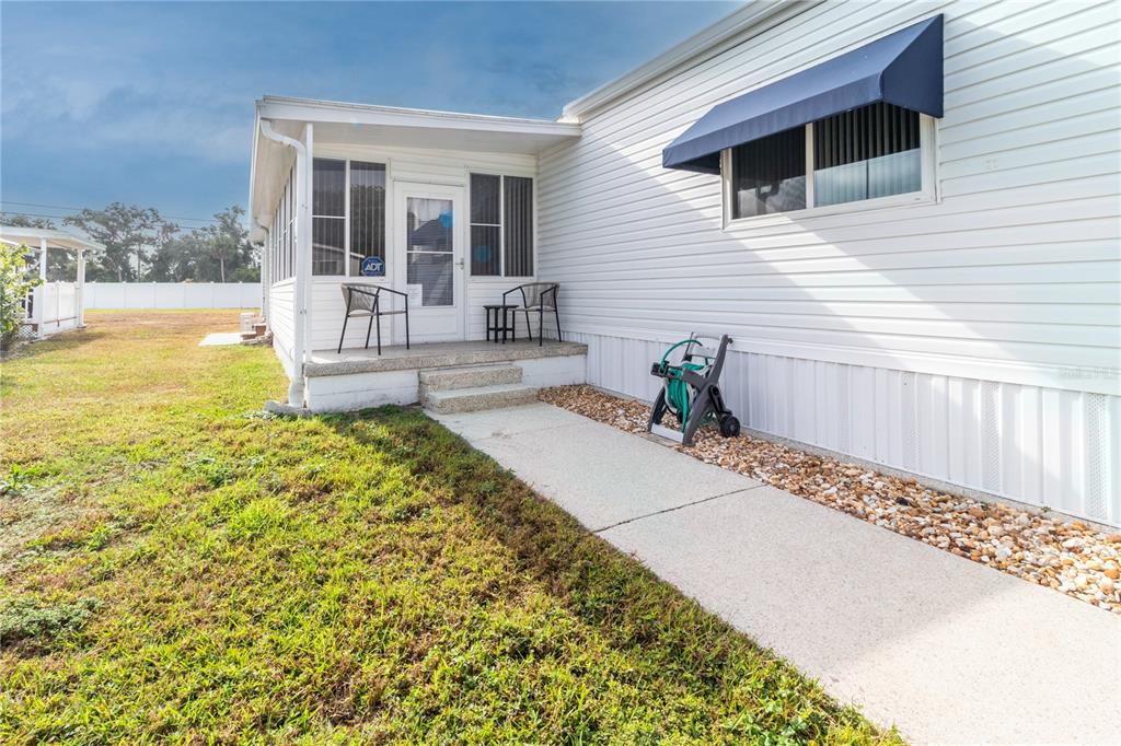 An exterior view of a mobile home with a concrete walkway and a small porch — 214 LEISURE WAY, PALMETTO, FL