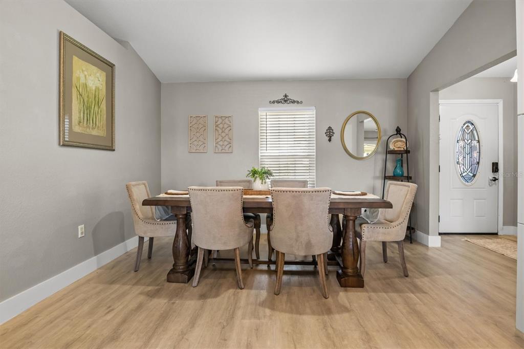 A dining room features a wooden table, upholstered chairs, light wood flooring, and gray walls — 5963 HILLSIDE HEIGHTS DRIVE, LAKELAND, FL