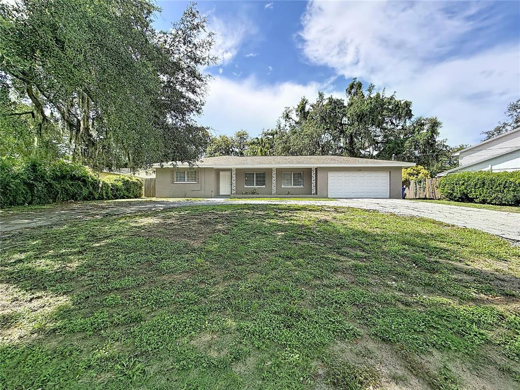 A single-story house with a gray exterior, white garage door, and a large front yard — 7123 WOODFIELD DRIVE, TAMPA, FL