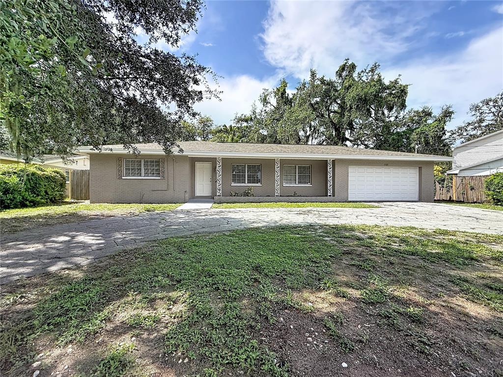 A single-story brick house with a white front door, two windows, and a two-car garage — 7123 WOODFIELD DRIVE, TAMPA, FL