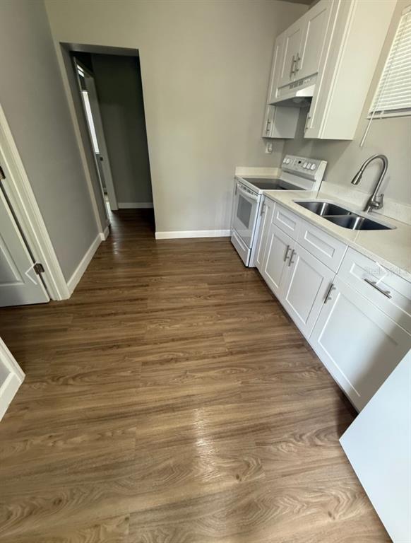 A kitchen features white cabinets, light-colored countertops, stainless steel appliances, and wood-look flooring — 962 19 AVENUE S UNIT C, ST PETERSBURG, FL