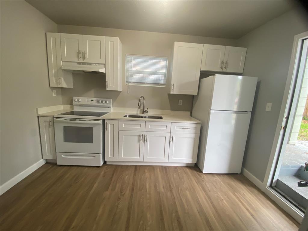 A kitchen features white cabinets, white appliances, a stainless steel sink, and wood-look flooring — 962 19 AVENUE S UNIT C, ST PETERSBURG, FL