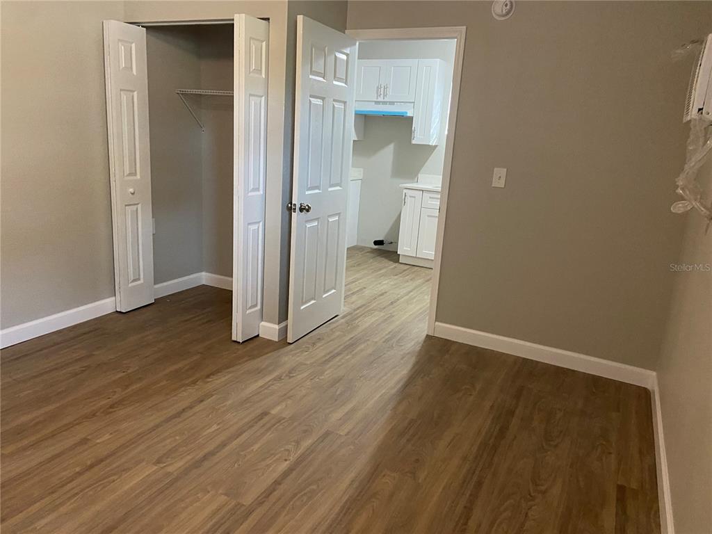 A room with wood-look flooring features a closet with white doors and an open doorway — 962 19 AVENUE S UNIT C, ST PETERSBURG, FL