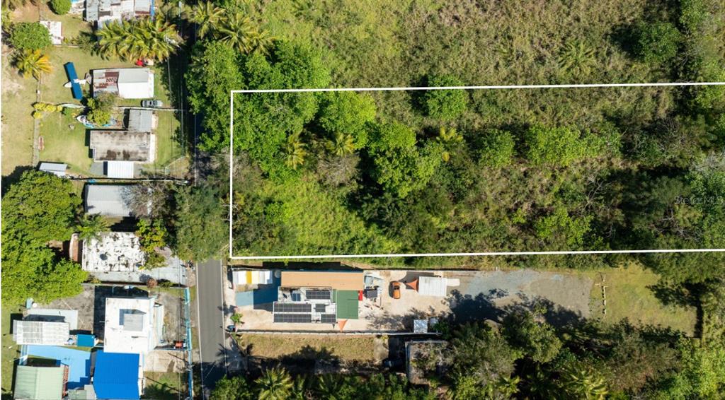 An aerial view shows a rectangular plot of land outlined in white next to a road — Carr 102 KM.HM 10.3 BO. GUANAJIBO, SECTOR JOYUDA, CABO ROJO, PR