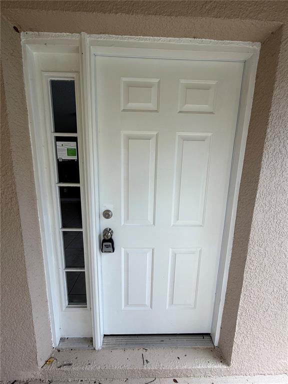 A white six-panel front door with a side window and a lockbox attached — 2413 RUDDENSTONE WAY, KISSIMMEE, FL