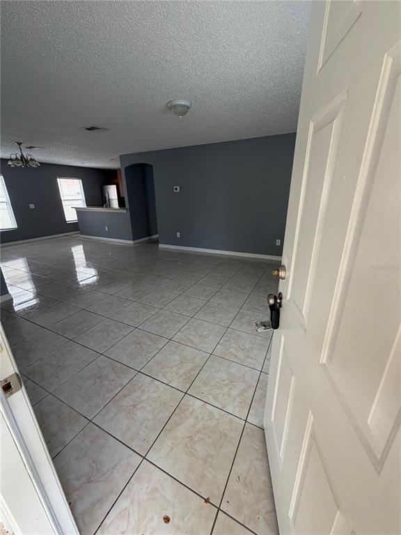 An open-concept living area features light-colored tile flooring and gray walls viewed from an entryway — 2413 RUDDENSTONE WAY, KISSIMMEE, FL