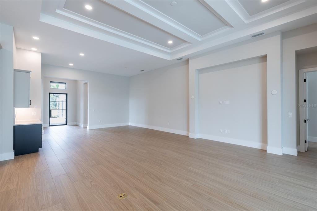A spacious living room features light wood-look tile flooring, a coffered ceiling, and a recessed wall — 268 BLUE PEARL CT,, SARASOTA, FL