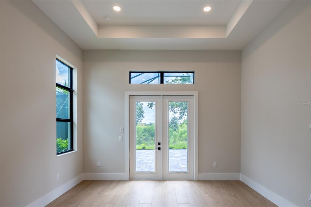 A room with light wood-look flooring, a tray ceiling, a side window, and double glass doors — 268 BLUE PEARL CT,, SARASOTA, FL