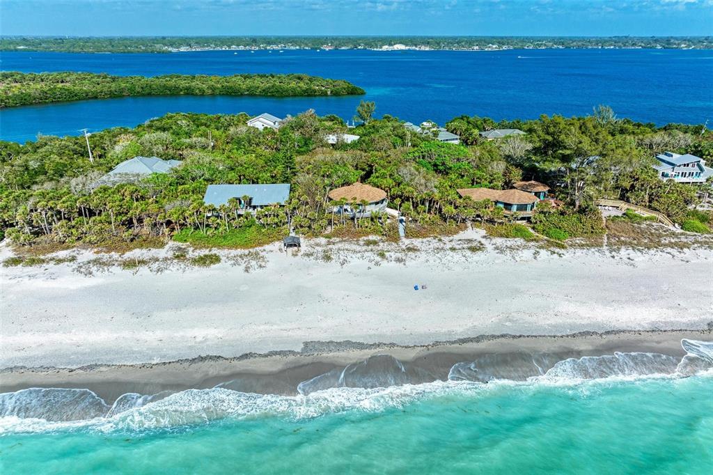 An aerial view shows several houses nestled in dense vegetation along a sandy beach — 6590 MANASOTA KEY ROAD, ENGLEWOOD, FL