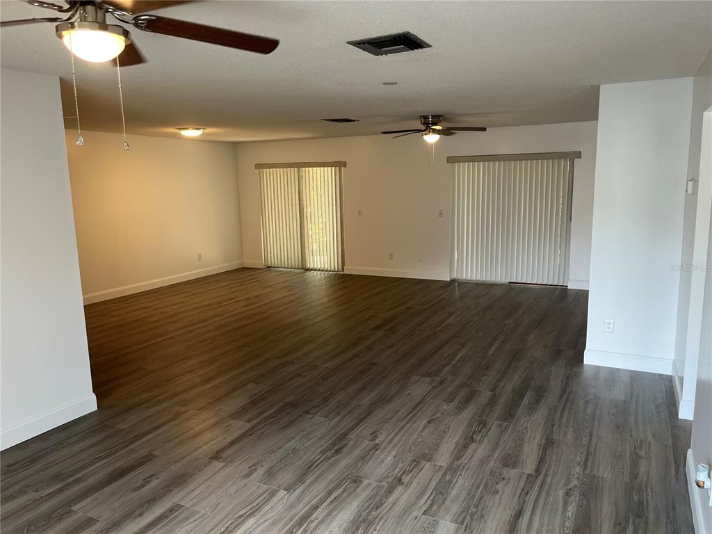 An open-concept living area features wood-look flooring, two ceiling fans, and sliding glass doors — 10108 BLUFF COURT, ORLANDO, FL