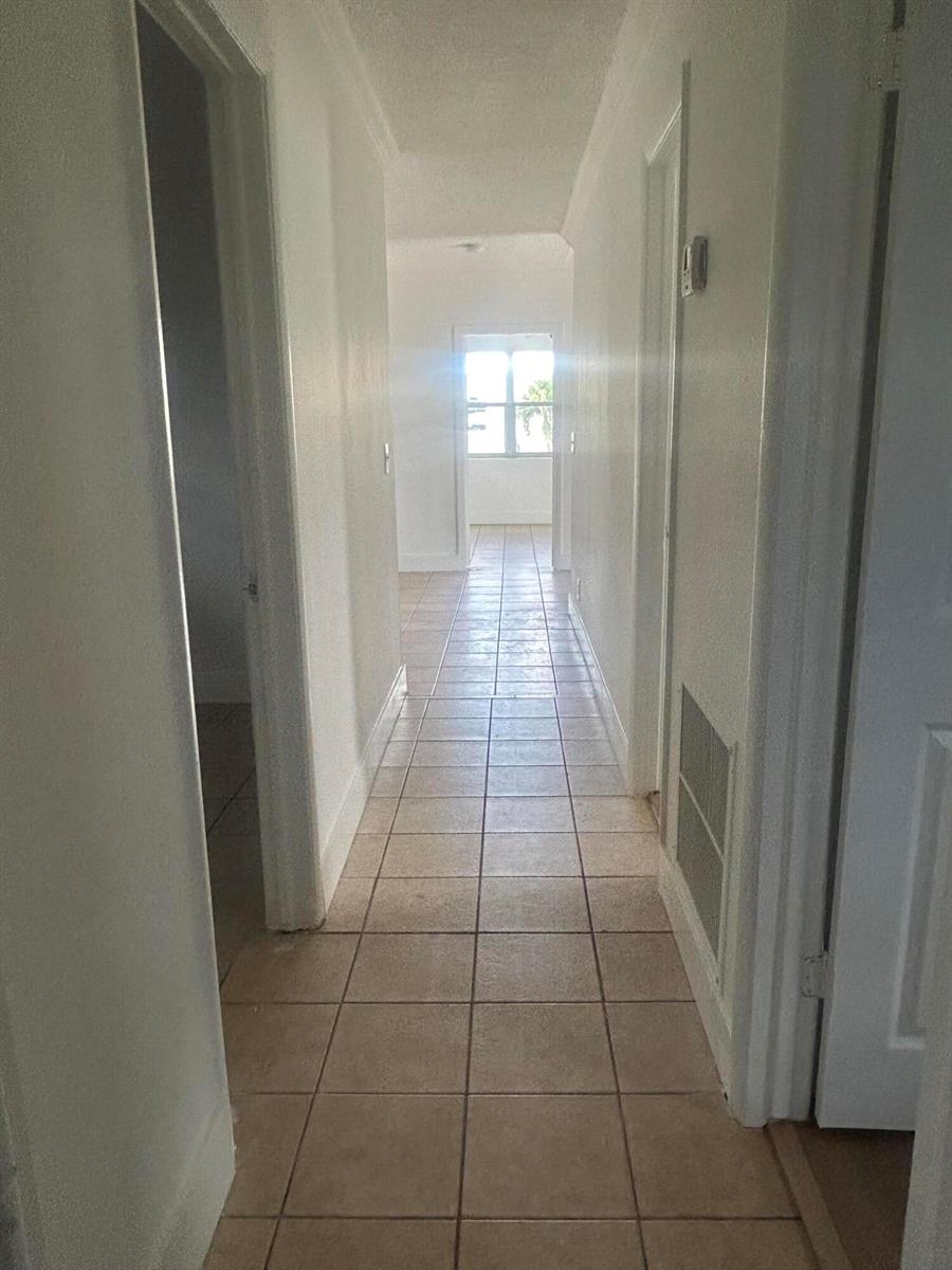 A tiled hallway leads toward a bright room with a window at the far end — 1528 S Avenue # 0, Riviera Beach FL 33404, RIVIERA BEACH, FL