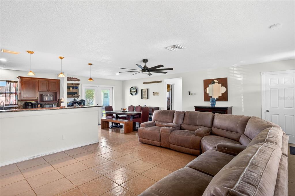 A spacious open-concept living room and dining area with tile flooring and a sectional sofa — 219 RICHMOND AVENUE S, LEHIGH ACRES, FL