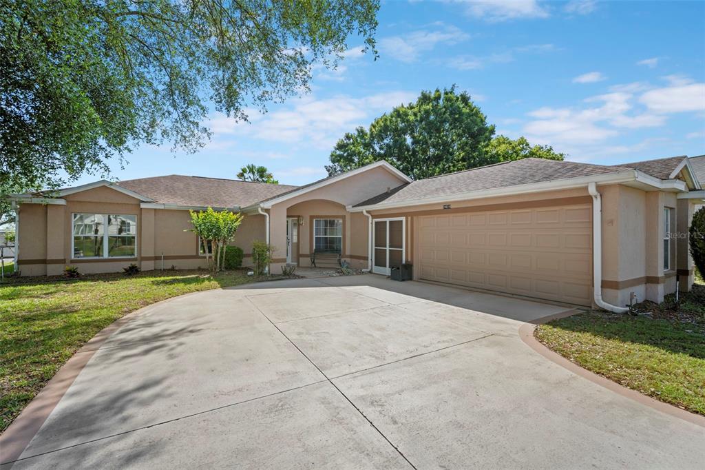 A tan, single-story house with a concrete driveway and an attached two-car garage — 24618 STILLRIDGE COURT, LEESBURG, FL