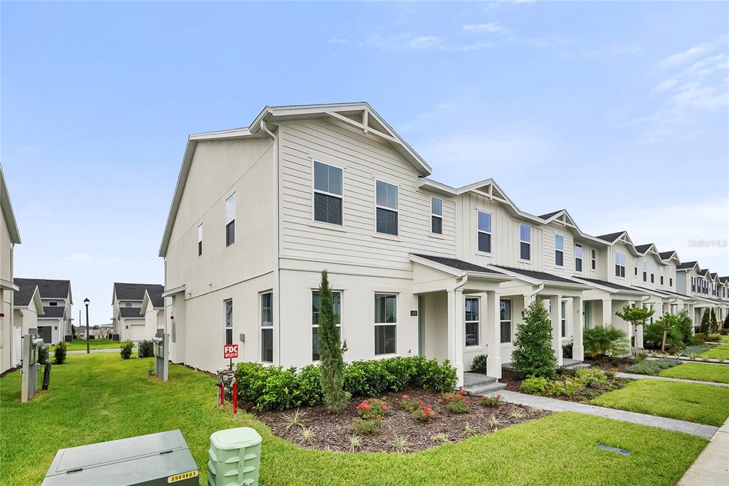 A row of two-story townhomes with light-colored siding and a grassy lawn in front — 1856 CROWNCREST DRIVE, APOPKA, FL