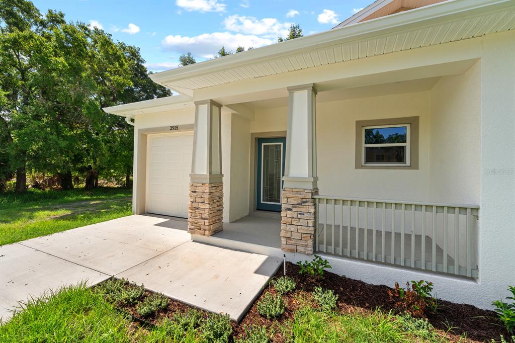A single-story house exterior features a covered porch, stone-based columns, and a white garage door — 2915 CHIPCO STREET, TAMPA, FL