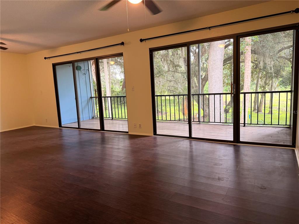 An empty room with dark wood flooring and two sets of sliding glass doors to balconies — 423 SHEOAH BOULEVARD UNIT 14, WINTER SPRINGS, FL