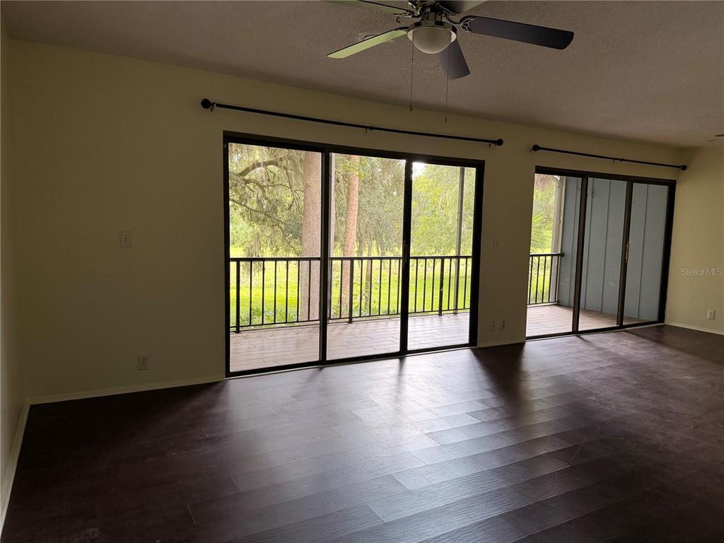 A living room with dark wood flooring, a ceiling fan, and sliding glass doors to a balcony — 423 SHEOAH BOULEVARD UNIT 14, WINTER SPRINGS, FL