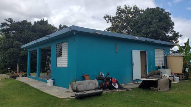 A teal, single-story concrete house with a covered porch and a large water tank outside — KM. 1.8 PR-678, VEGA ALTA, PR