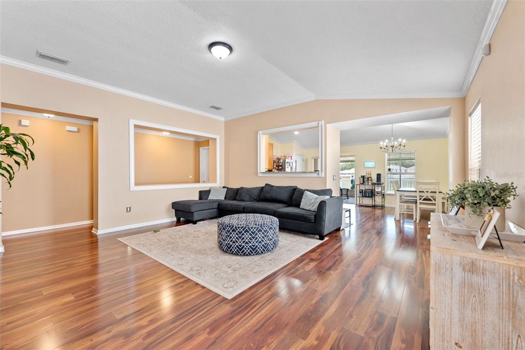 A living room with dark wood floors, a gray sectional sofa, and a patterned ottoman — 13508 RED EAR COURT, RIVERVIEW, FL
