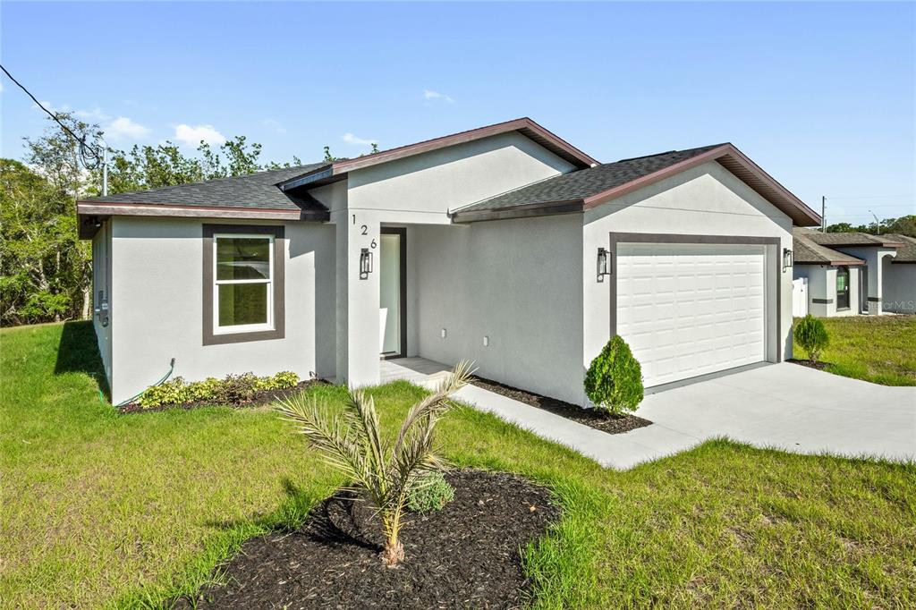 A single-story house with a white stucco exterior, a two-car garage, and a small palm tree — 126 CANBY CIRCLE, SPRING HILL, FL
