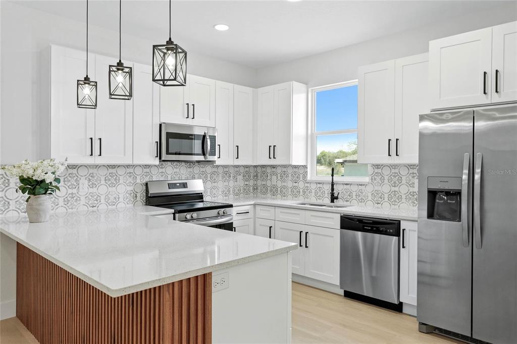 A modern kitchen features white cabinets, stainless steel appliances, a patterned backsplash, and a wood-paneled island — 126 CANBY CIRCLE, SPRING HILL, FL