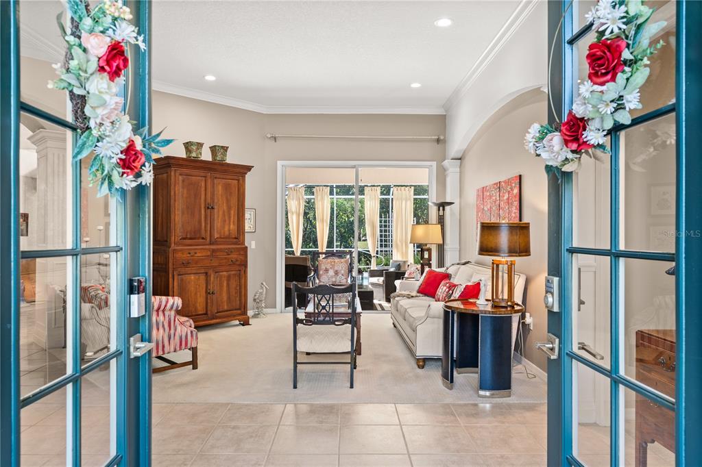 A view through double glass doors into a living room with a sofa and armoire — 8224 WATERVIEW BOULEVARD, LAKEWOOD RANCH, FL